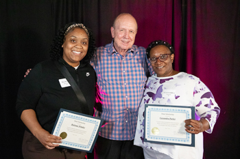 A young woman holding a certificate while standing next to an adult.