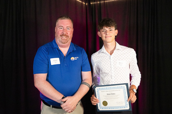 A teenager holding a certificate while standing next to an adult.