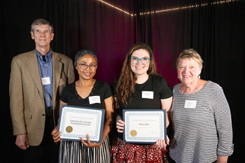 A group of four people standing, looking at the camerea.