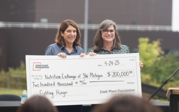 Two women hold a large check for $200,000/