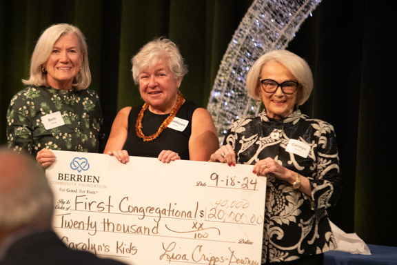 Three people holding a check