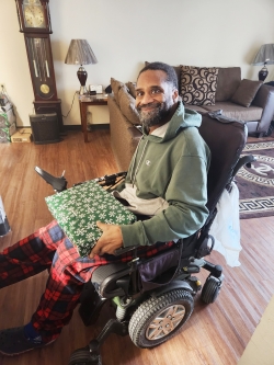 A man in a wheelchair holding a christmas present. 