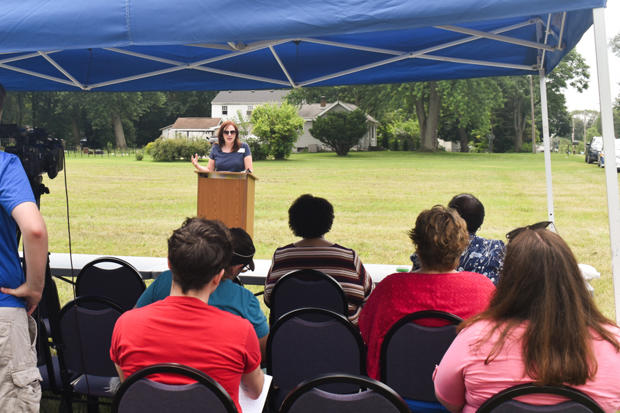 A woman stands at a podium in front of a crowd. 