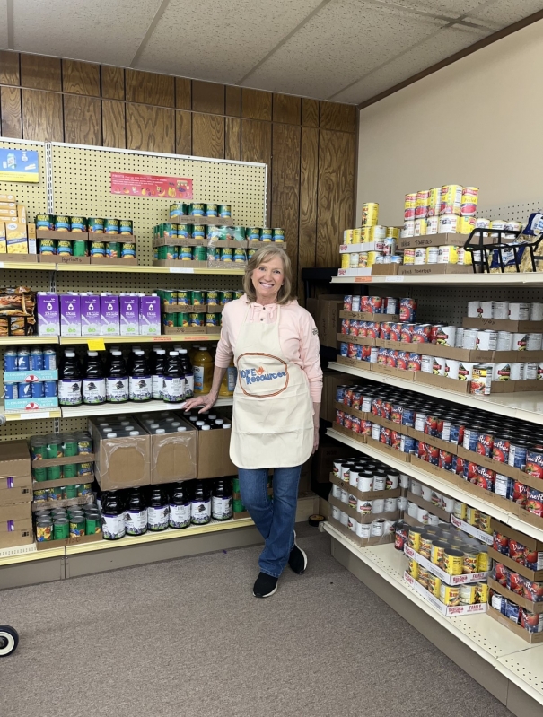 A woman standing in front of shelving full of canned food. 